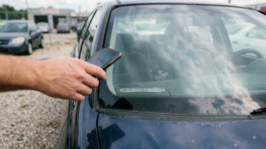 A man taking a picture of VIN from a car's dashboard.